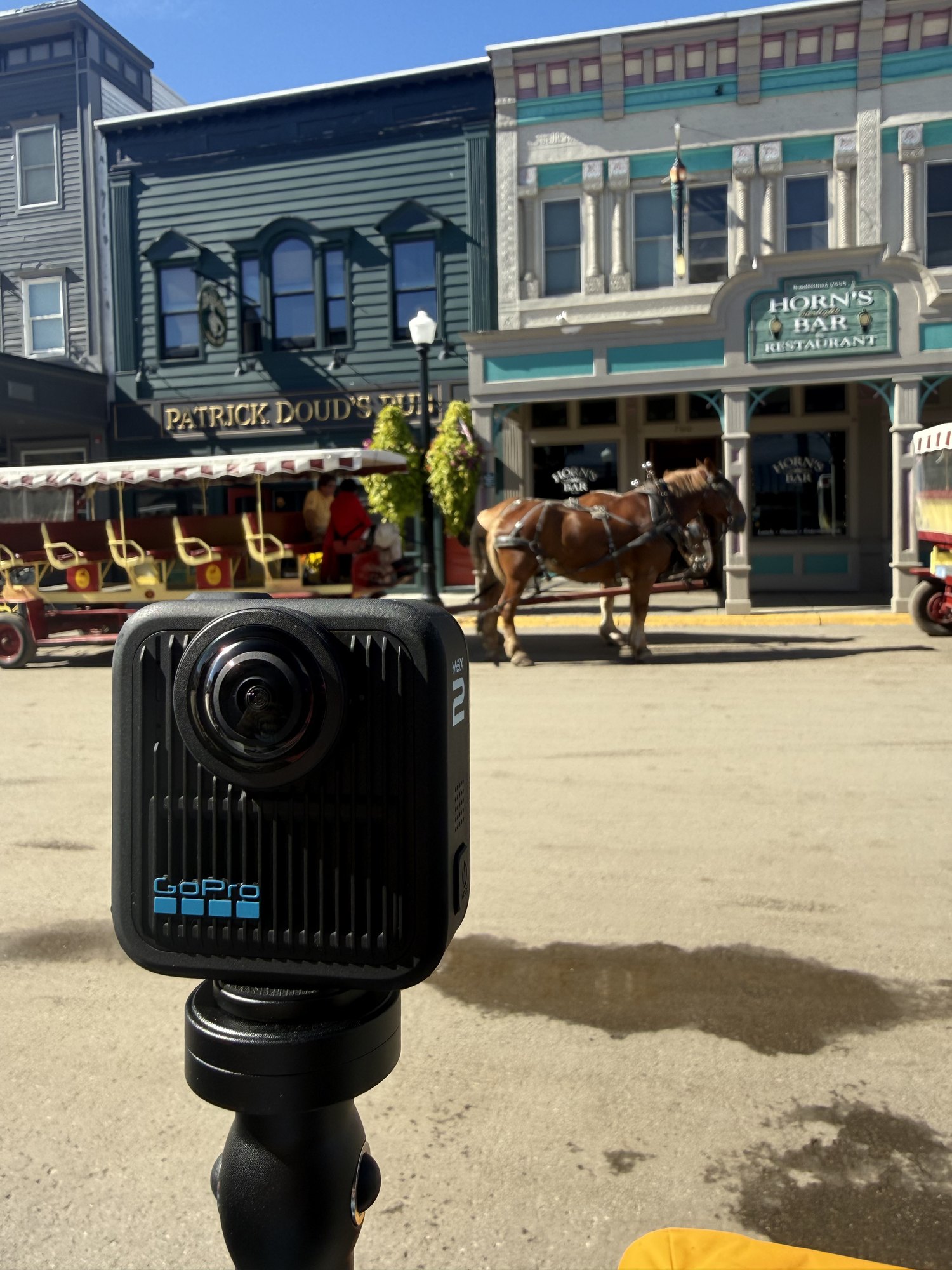 A GoPro Max 2 on a pole on Main Street, Mackinac Island, with a horse and carriage outside Horn's Bar behind it